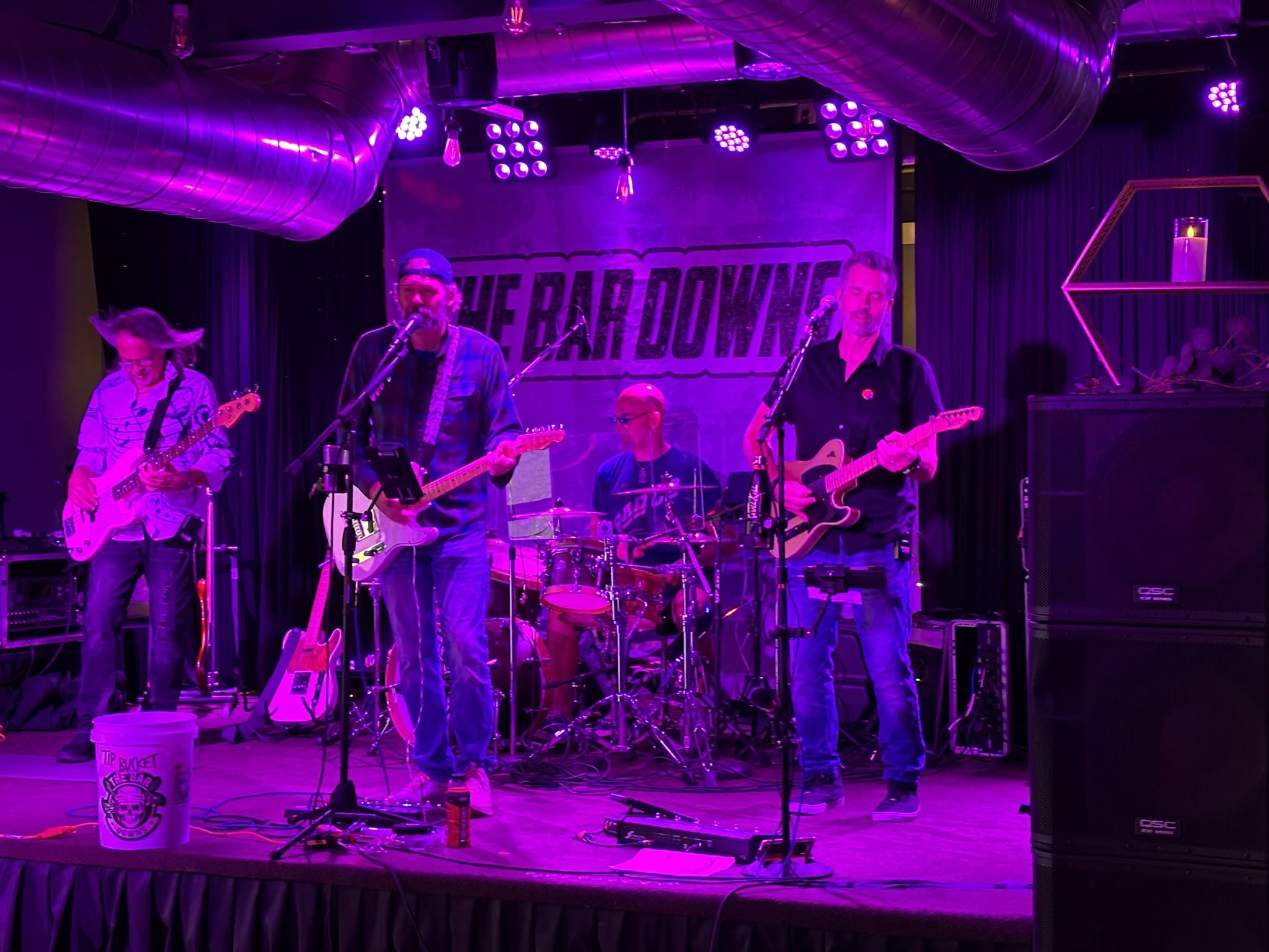The full band performing under purple stage lights